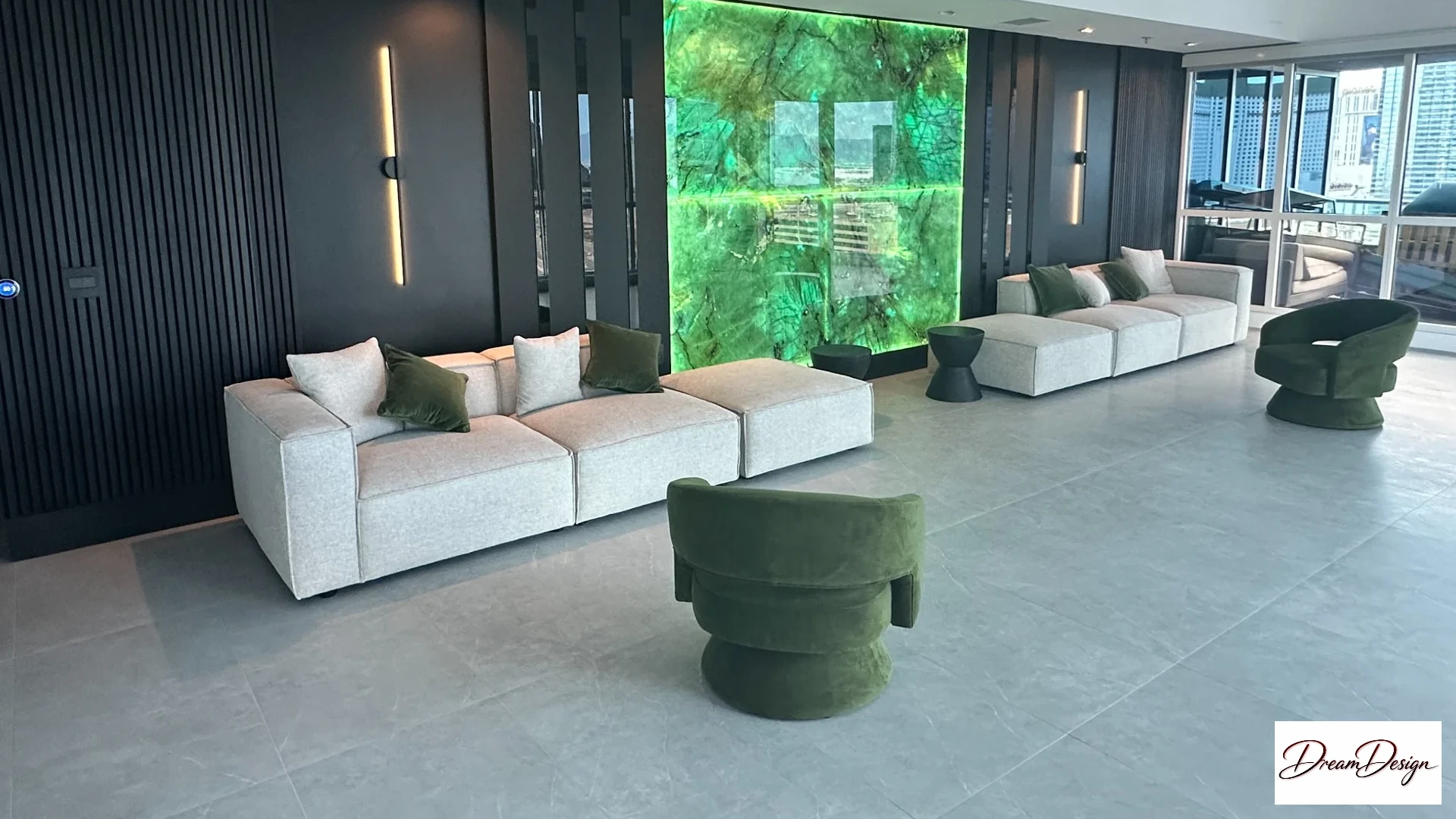 Living room with pale sofas, green chairs, dark wall panels and an illuminated green feature wall.