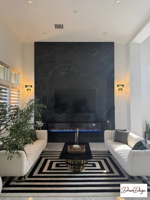Straight-on view of a tall dark veined fireplace and television wall between light sofas.