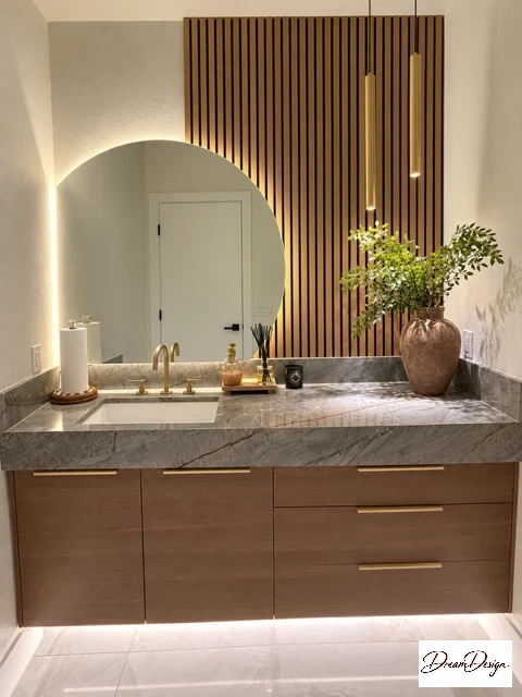 Floating wood-grain vanity, veined countertop, round backlit mirror and vertical wood-tone slat wall.