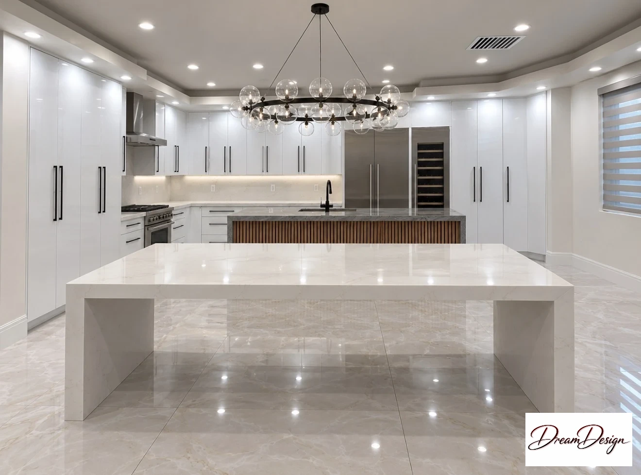 White kitchen cabinetry with black pulls, a wood-slat island front and a large pale waterfall-edge surface.