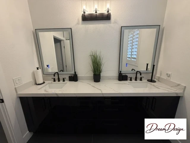 Black double vanity with a pale veined countertop, paired rectangular mirrors and black fixtures.
