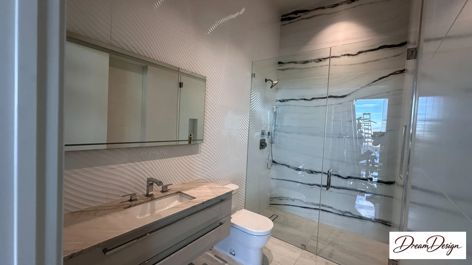 Pale vanity and a glass shower with strongly veined wall panels and a window.