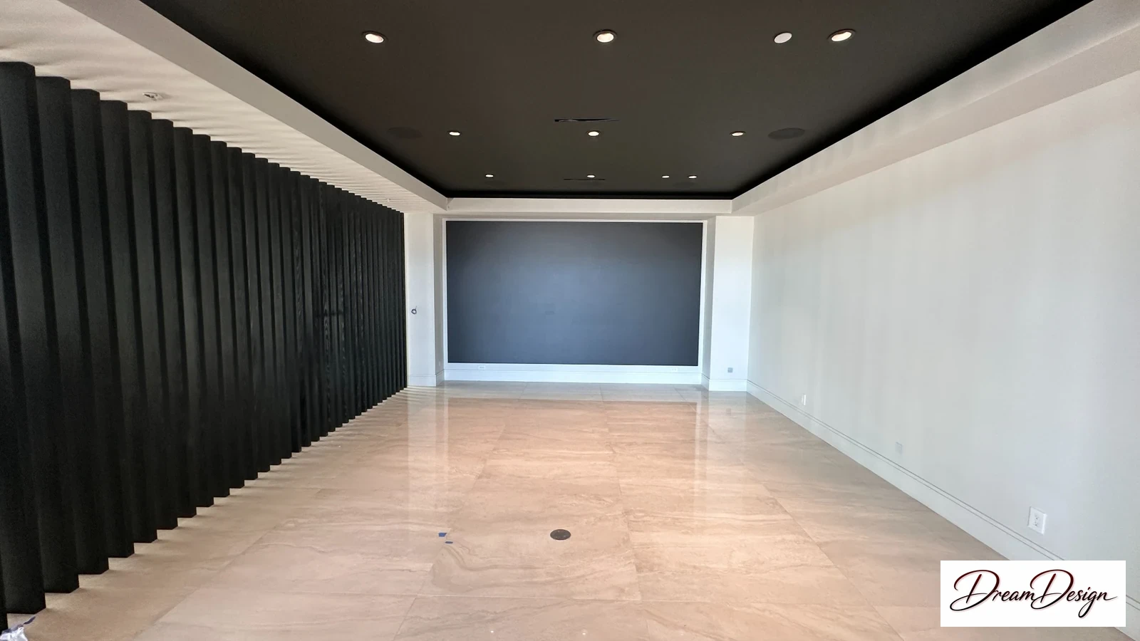 Dark vertical wall slats, a large recessed screen area and a light wood-tone floor.