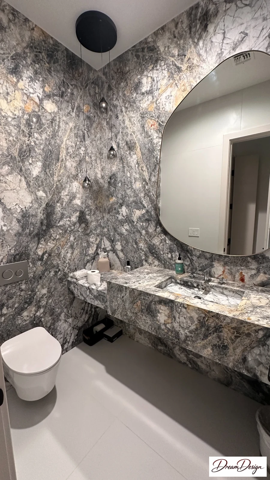 Round mirror and a floating vanity surrounded by richly patterned light and dark stone-effect surfaces.