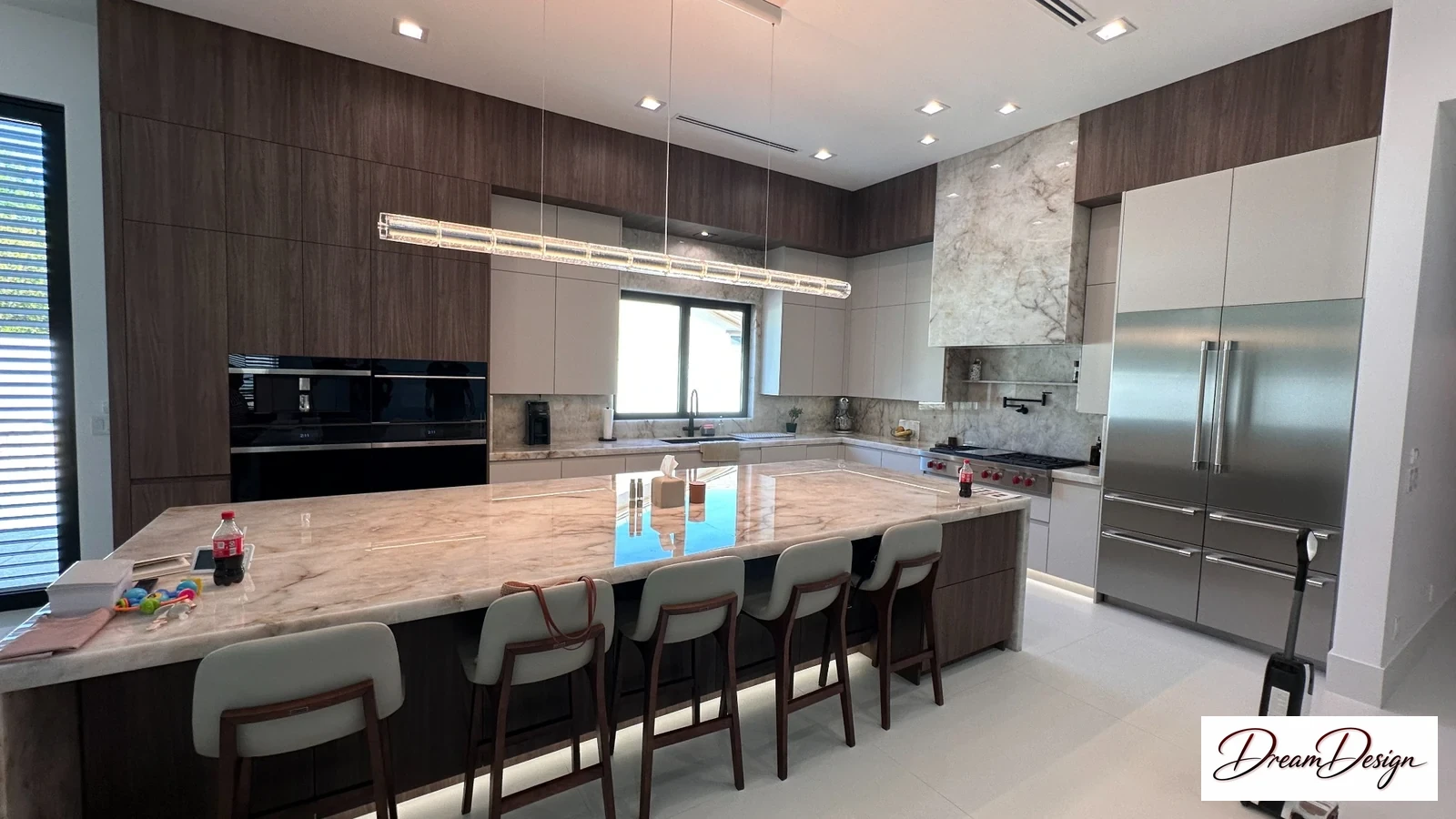 Tall wood-grain cabinetry, pale lower cabinets and an illuminated island in a contemporary kitchen.
