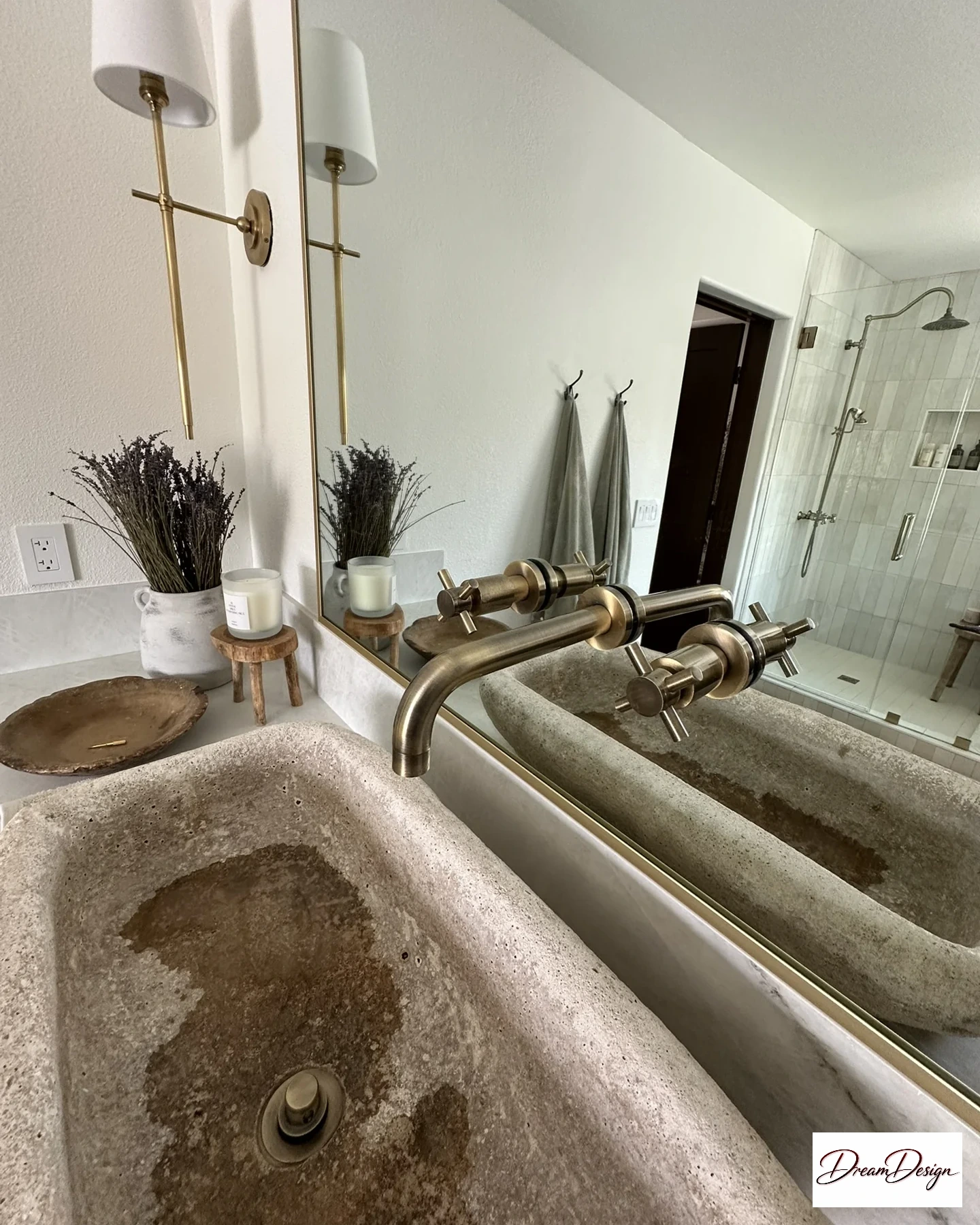 Textured vessel basin with a gold-tone wall-mounted faucet and a large rectangular mirror.