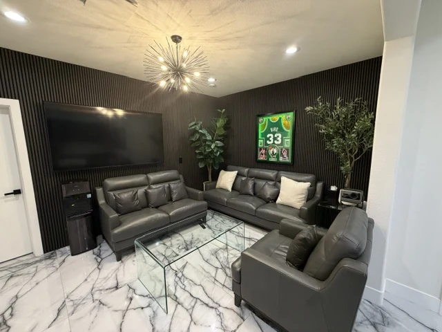 Lounge with dark vertical slat walls, dark seating and a light dramatically veined floor.