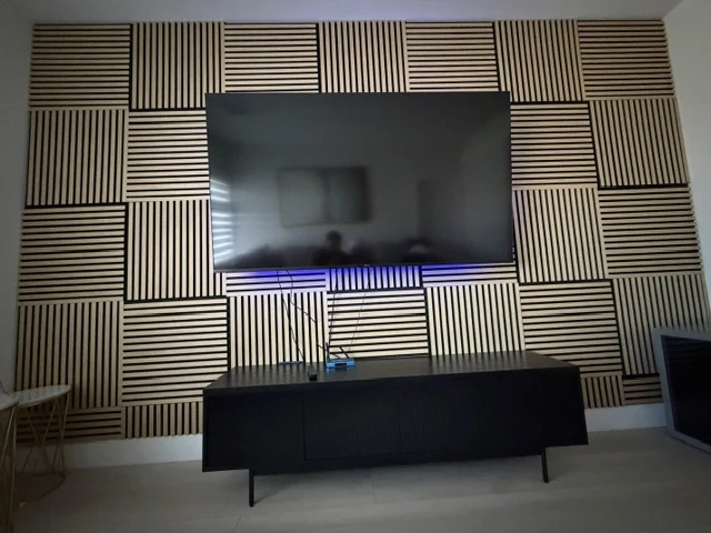 Television wall with square wood-slat panels arranged in alternating directions and a dark cabinet below.
