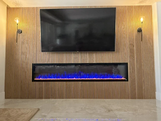 Vertical wood-tone slat wall with a television, linear fireplace and two wall lights.